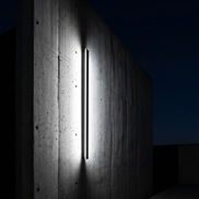 Vertical linear LED light grazing a concrete facade wall, cool white
