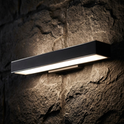 Close-up of rectangular LED wall light glowing on stone wall at night