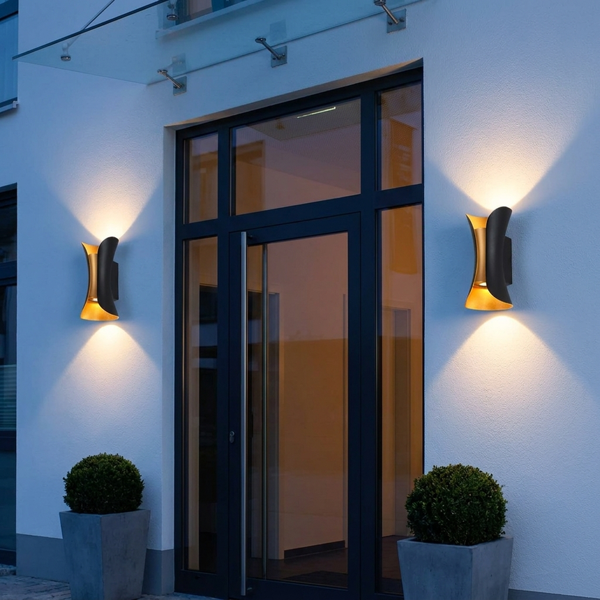 Pair of arc up-down wall lights on white wall flanking a glass entry at night